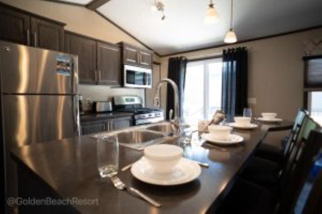 uma cozinha com uma mesa com pratos e um frigorífico em 3 Bedroom Waterview Cottage 4B em Roseneath