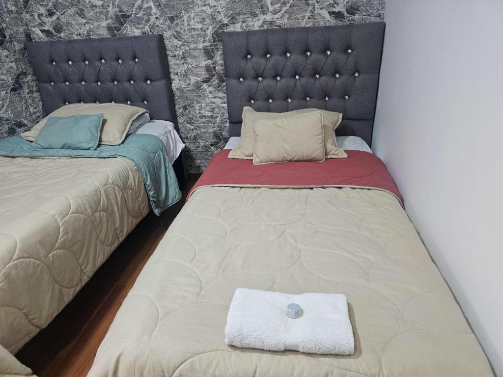 um quarto com duas camas e uma almofada no chão em Colisseum Roma - El cubo movistar campin em Bogotá