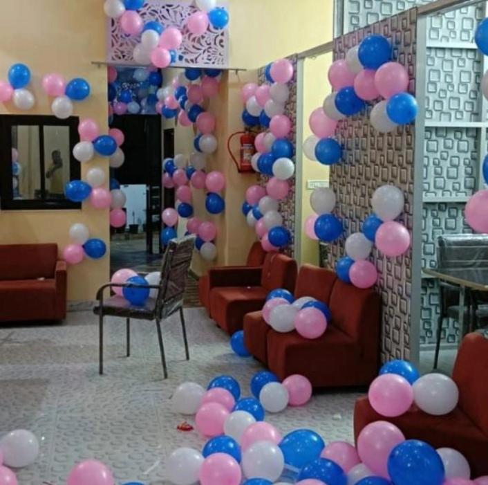 een kamer met roze en blauwe ballonnen en banken bij Mg hotel in Bīr