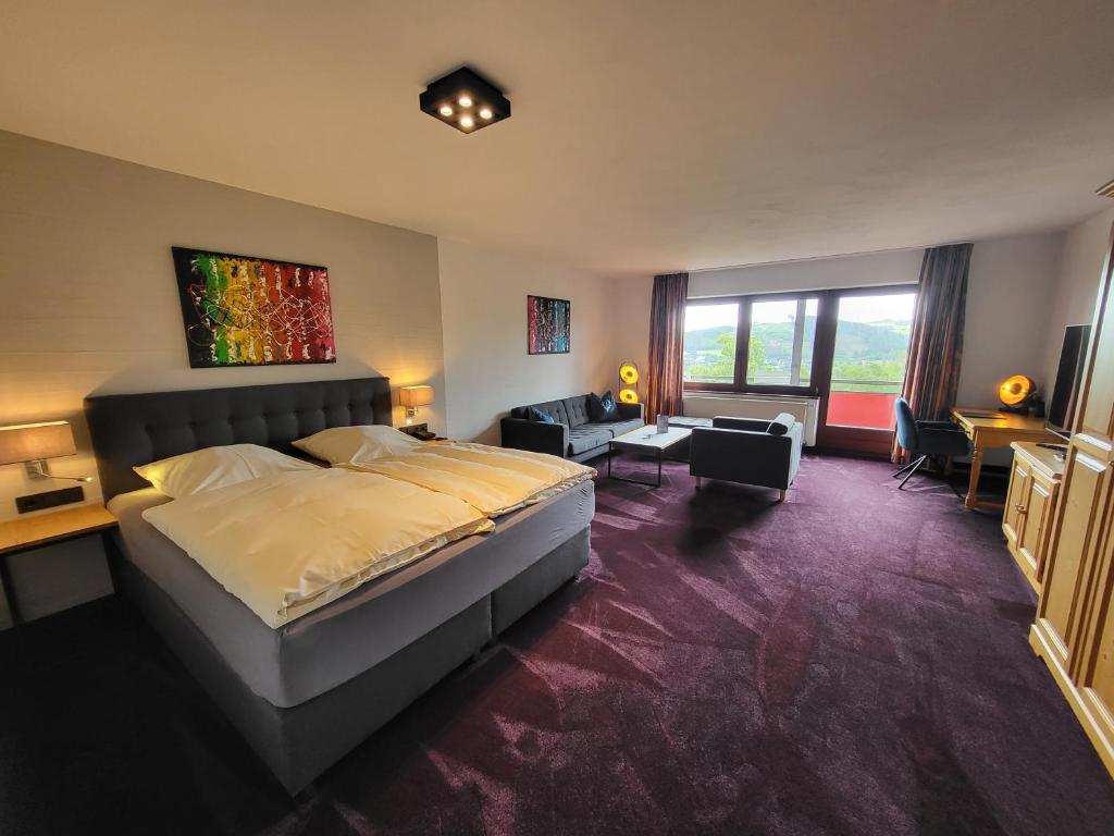 a bedroom with a large bed and a living room at Berghotel Habbel und die Welt kann warten in Cobbenrode