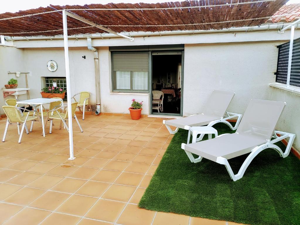 un patio con sillas blancas, mesa y sillas en Loft El Carmen, en Teruel