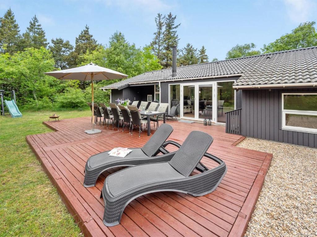eine Terrasse mit Stühlen, einem Tisch und einem Sonnenschirm in der Unterkunft Holiday Home Liviana - all inclusive - from the sea by Interhome in Blåvand