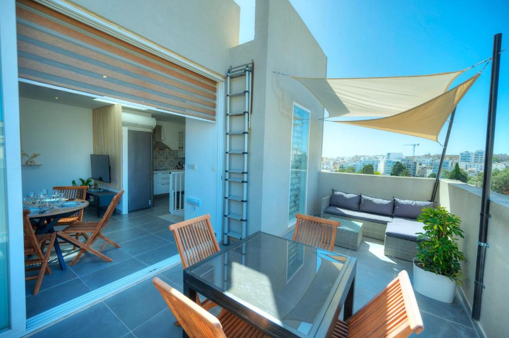 uma varanda com uma mesa de vidro e cadeiras em Charming, modern 2bedroom with sun terrace EGUE1-1 em St. Julian's