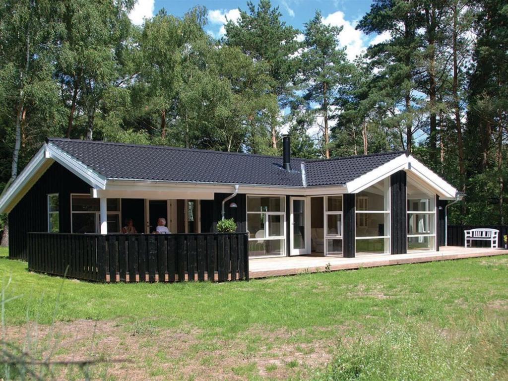 een huis met een zwart dak en een veranda bij Holiday Home Elisenda - all inclusive - 625m from the sea by Interhome in Skagen