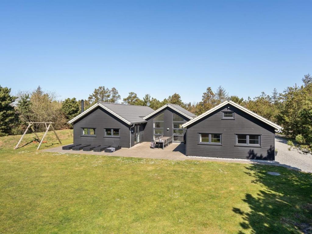 een zwart huis met een speeltuin ervoor bij Holiday Home Lova - all inclusive - 600m from the sea by Interhome in Blåvand