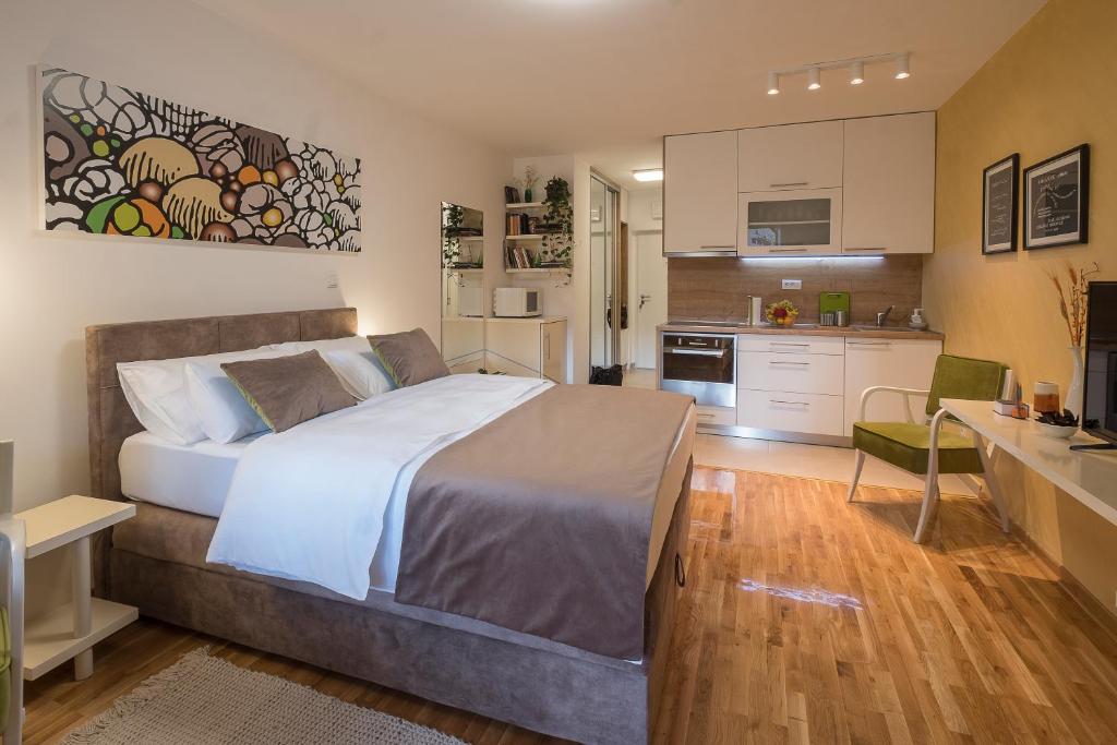 a bedroom with a large bed and a kitchen at Cozy studio with a terrace near Slavija square in Sajmište
