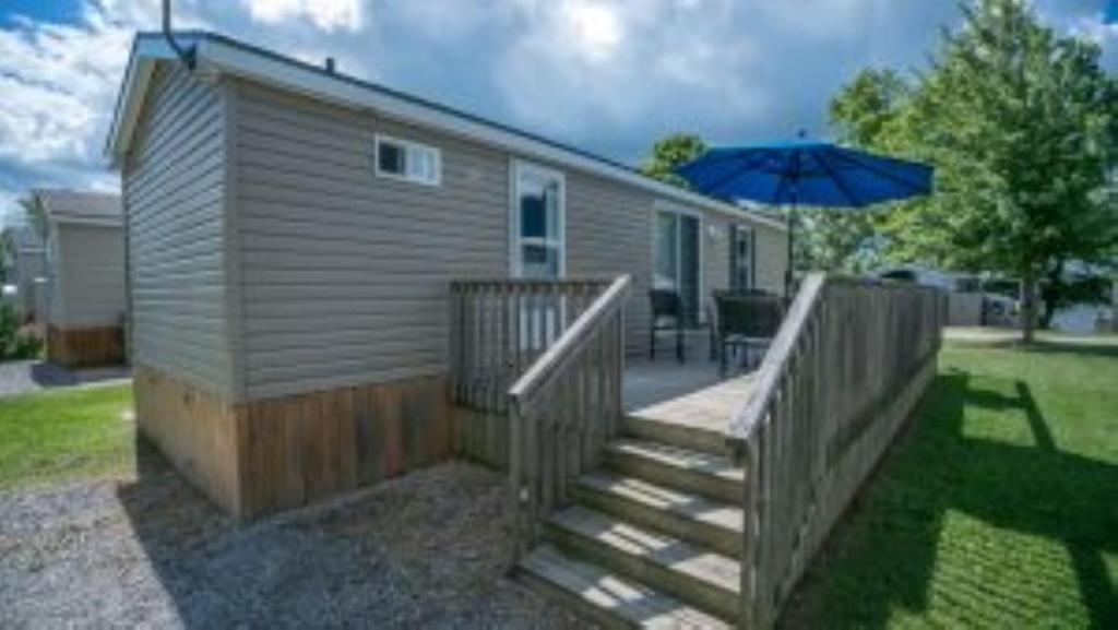 Casa pequeña con terraza y sombrilla en 3 Bedroom Cottage Tamarack Trail 5, en Campbellford