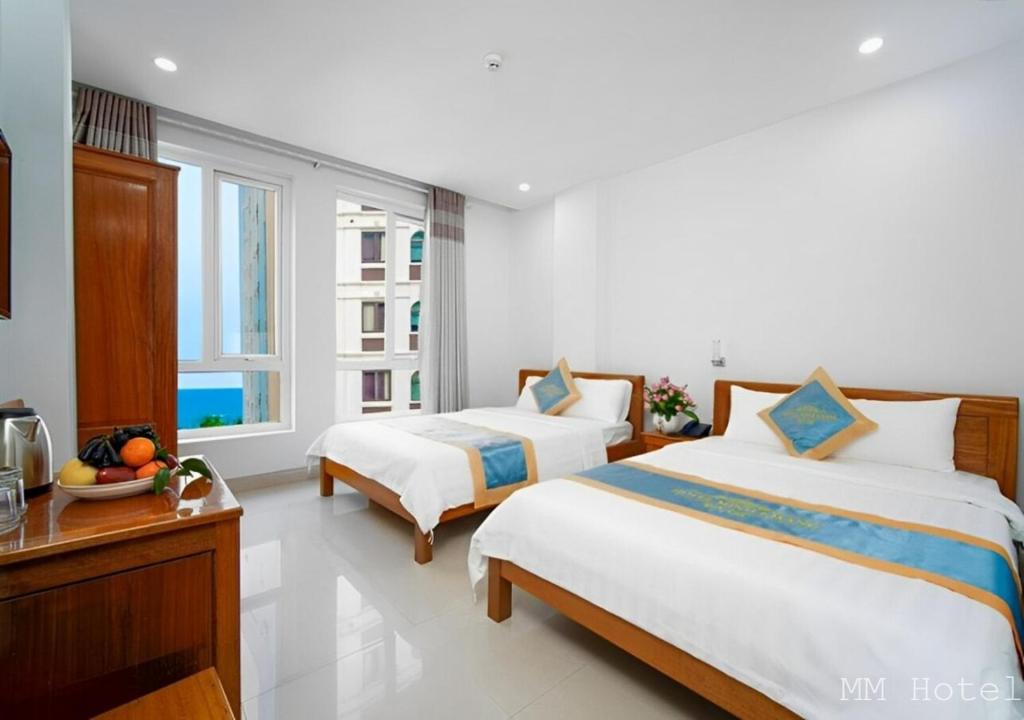 a bedroom with two beds and a table and two windows at Minh Minh Hotel & Spa in Da Nang