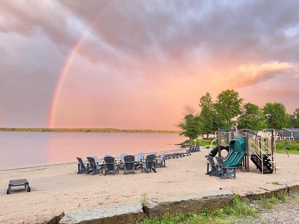 un arco iris en el cielo sobre un patio de juegos con una persona en Newly Renovated 2 Bedroom Beach Front Condo 1C, en Lanark