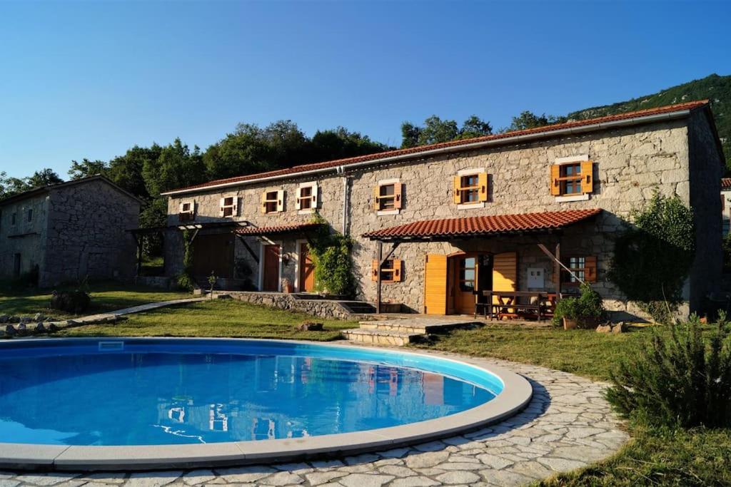 een huis met een zwembad voor een gebouw bij Villa Millefoglie, a century-old stone house nestled in a nature park in Lupoglav
