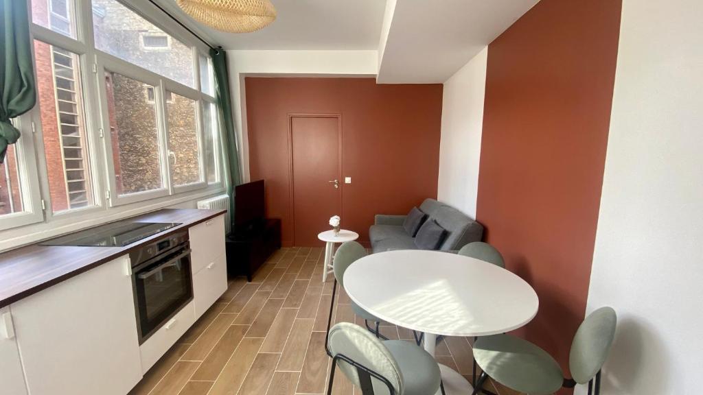 une petite cuisine avec une table et des chaises blanches dans l'établissement Appartement confortable proche Grands Boulevard 4P, à Paris