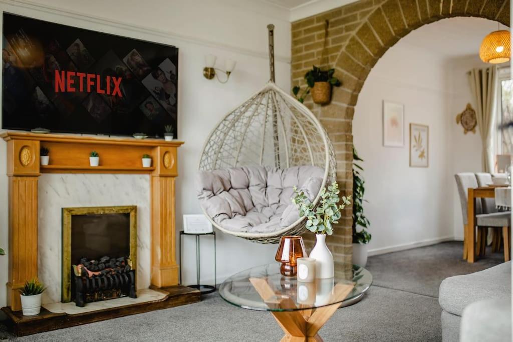 een woonkamer met een hangstoel en een open haard bij Serene Boho Retreat: White Oak Charm House 7ppl in Sheffield