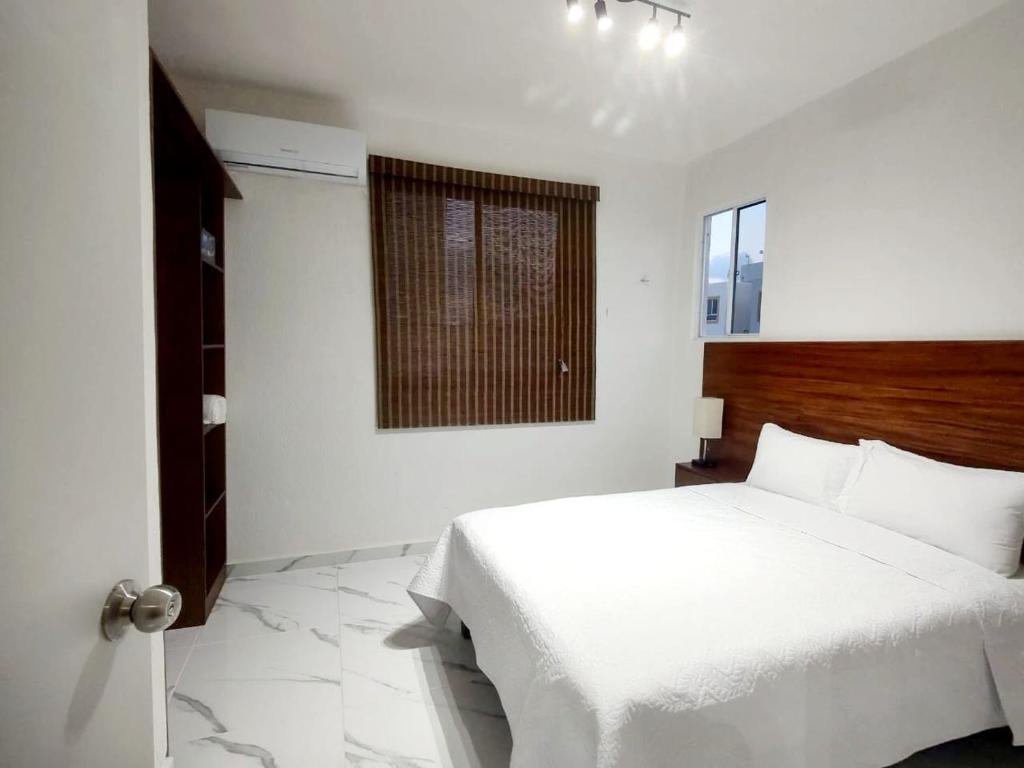 a bedroom with a white bed and a window at Departamento en tulum Quintana roo in Tulum