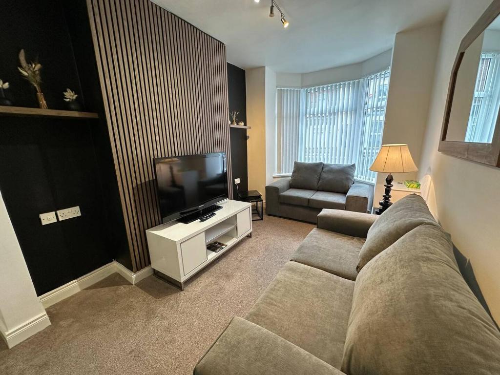 a living room with a couch and a television at 2br Stylish Ormeau Road House in Belfast