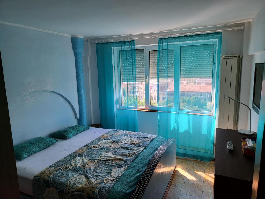 a bedroom with a bed with blue walls and windows at Apartament cu 2 dormitoare ,ultracentral in Arad