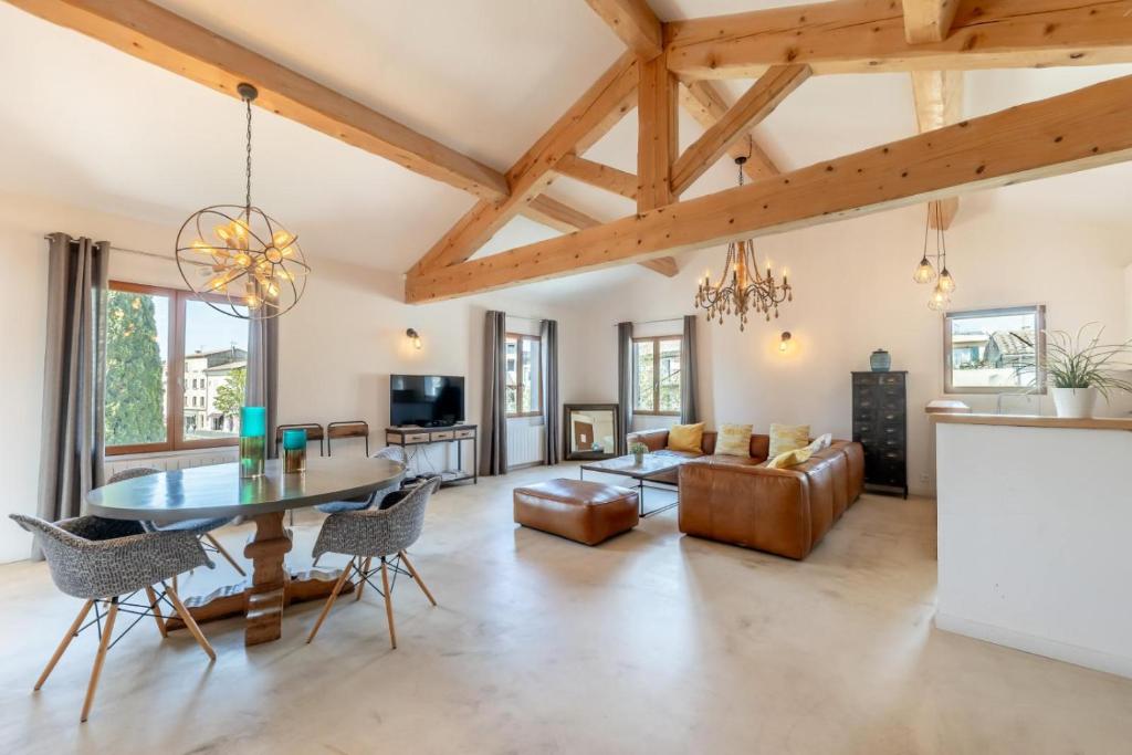 a dining room and living room with wooden ceilings at Olive- Vaste appartement donnant sur la Sorgue in LʼIsle-sur-la-Sorgue