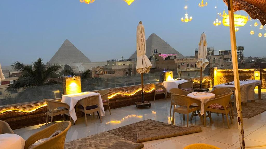 カイロにあるPyramids Express View HoTeLのテーブルと椅子、ピラミッドのあるレストラン