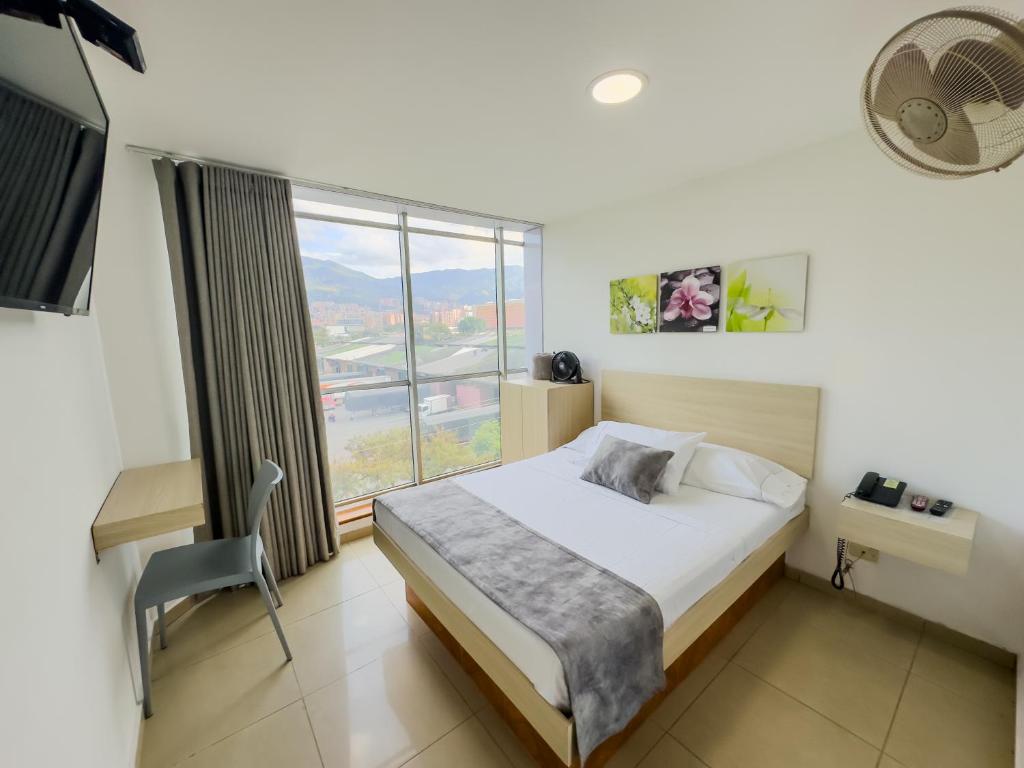 a bedroom with a bed and a desk and a window at Hotel Alcaravan Medellín in Medellín