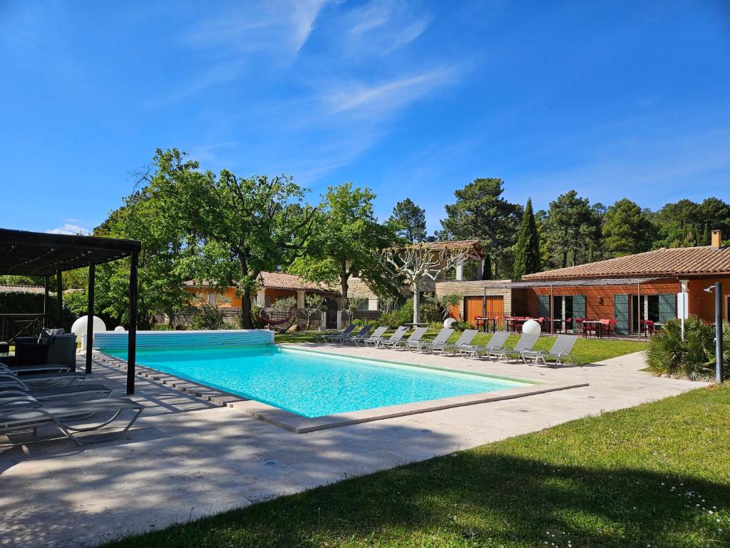 une piscine avec des chaises longues et une maison dans l'établissement Les Sables d'Ocre & SPA, à Roussillon