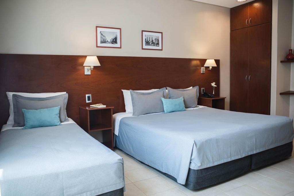 two beds in a hotel room with blue pillows at DonSuites in Corrientes