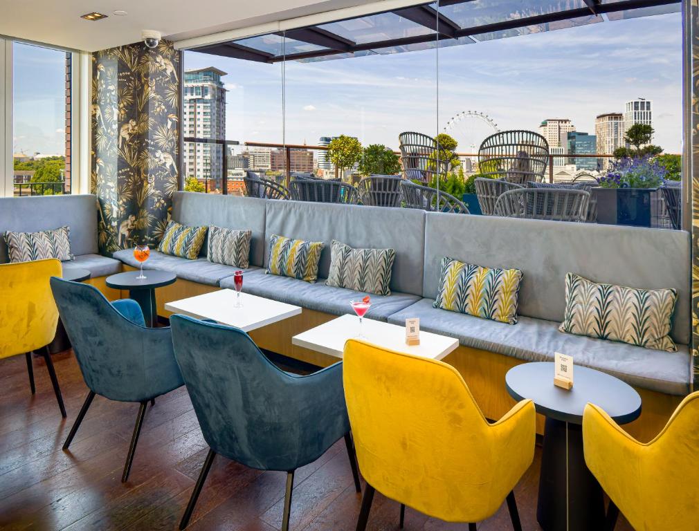 un restaurante con mesas y sillas y un sofá en H10 London Waterloo en Londres