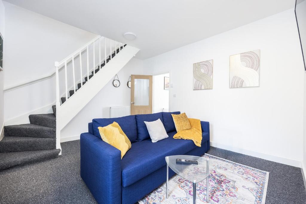 a blue couch in a living room with stairs at 4 beds home, 3 baths, sleeps 8, free parking, contractors, trades in Purfleet