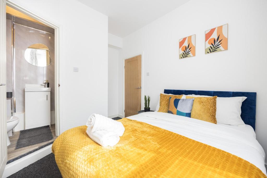a bedroom with a large bed with a yellow blanket at 4 beds home, 3 baths, sleeps 8, free parking, contractors, trades in Purfleet