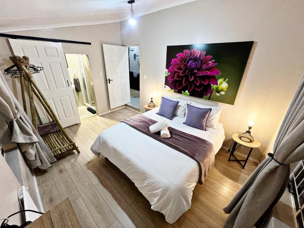 1 dormitorio con 1 cama con una pintura floral en la pared en Lincoln Moon Guesthouse, en Graskop