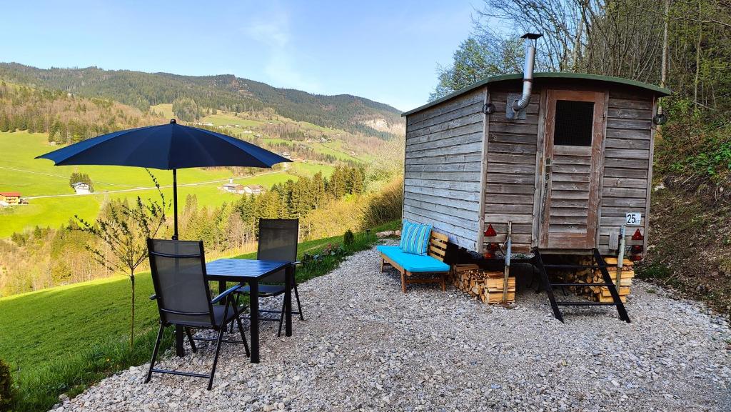 a table and chairs with an umbrella next to a cabin at Schäferhütte in Krispl