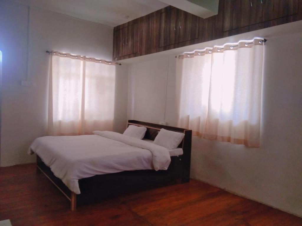 a bedroom with a bed with white sheets and a window at BN Resort in Gangolihāt