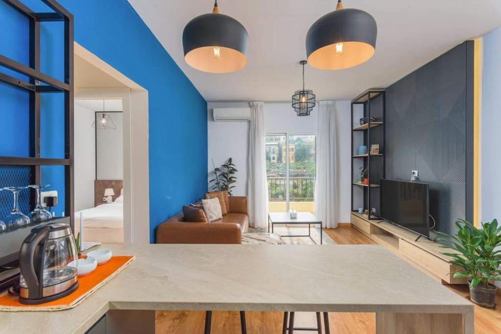 a kitchen and living room with blue walls and a table at Alice 2-BR in Mar Mikhael in Beirut