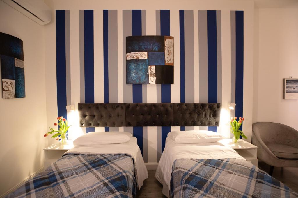 two beds in a room with blue and white stripes at Bru Rooms in Peschiera del Garda