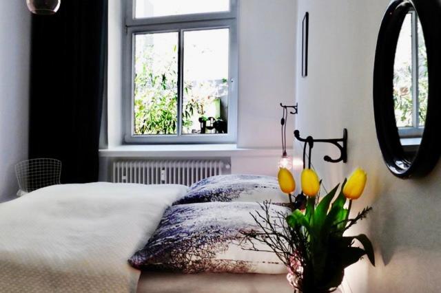 - une chambre avec un lit et un vase orné de fleurs jaunes dans l'établissement Apartments "Am Rheinorange", Netflix, Amazon Prime, à Duisbourg
