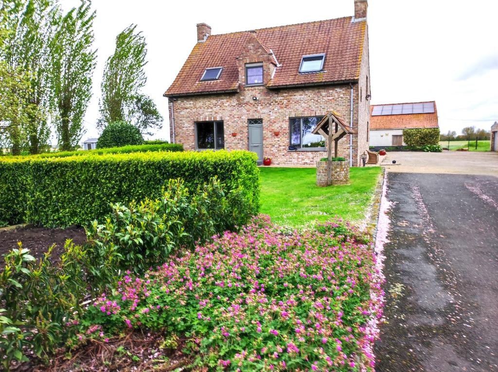 une maison en briques avec des fleurs devant une allée. dans l'établissement B&B Het Polderhof, à Jabbeke