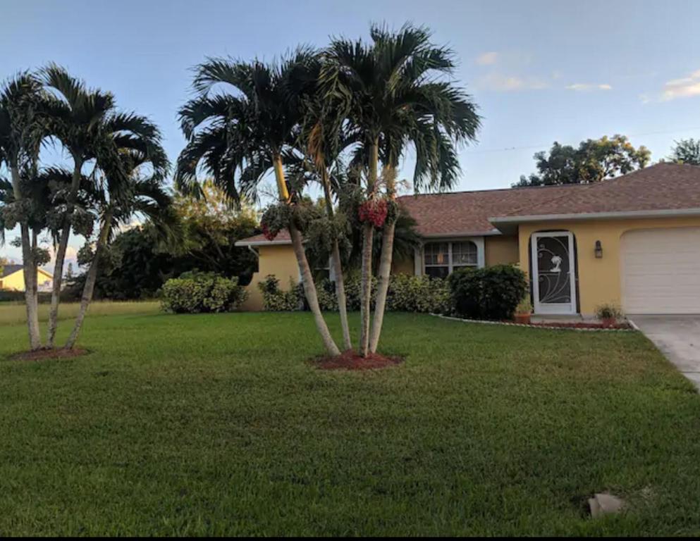een huis met twee palmbomen in een tuin bij Sunshine Home in Cape Coral