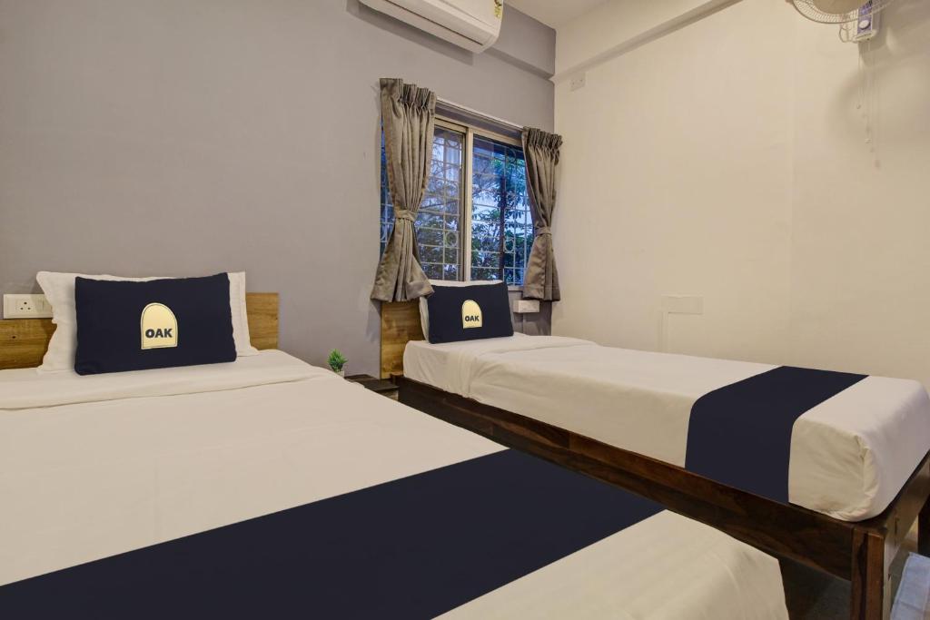 twee bedden in een kamer met een raam bij Grey House in Pune
