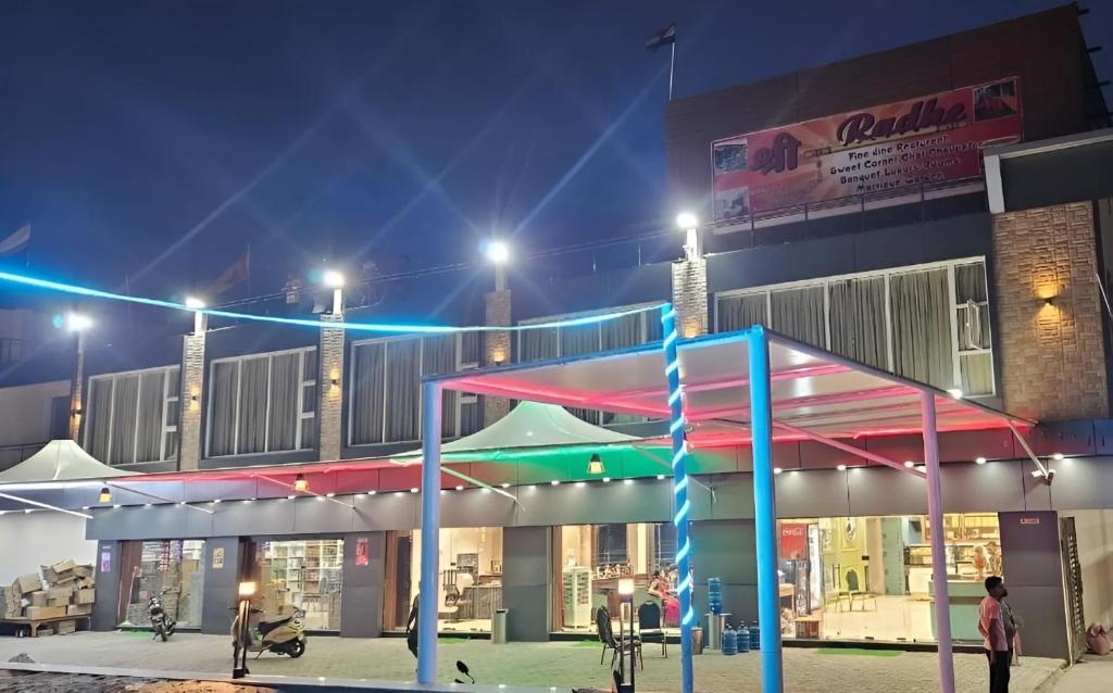 Un bâtiment avec des personnes debout devant lui la nuit dans l'établissement Sri Radhe Resort, à Supaul