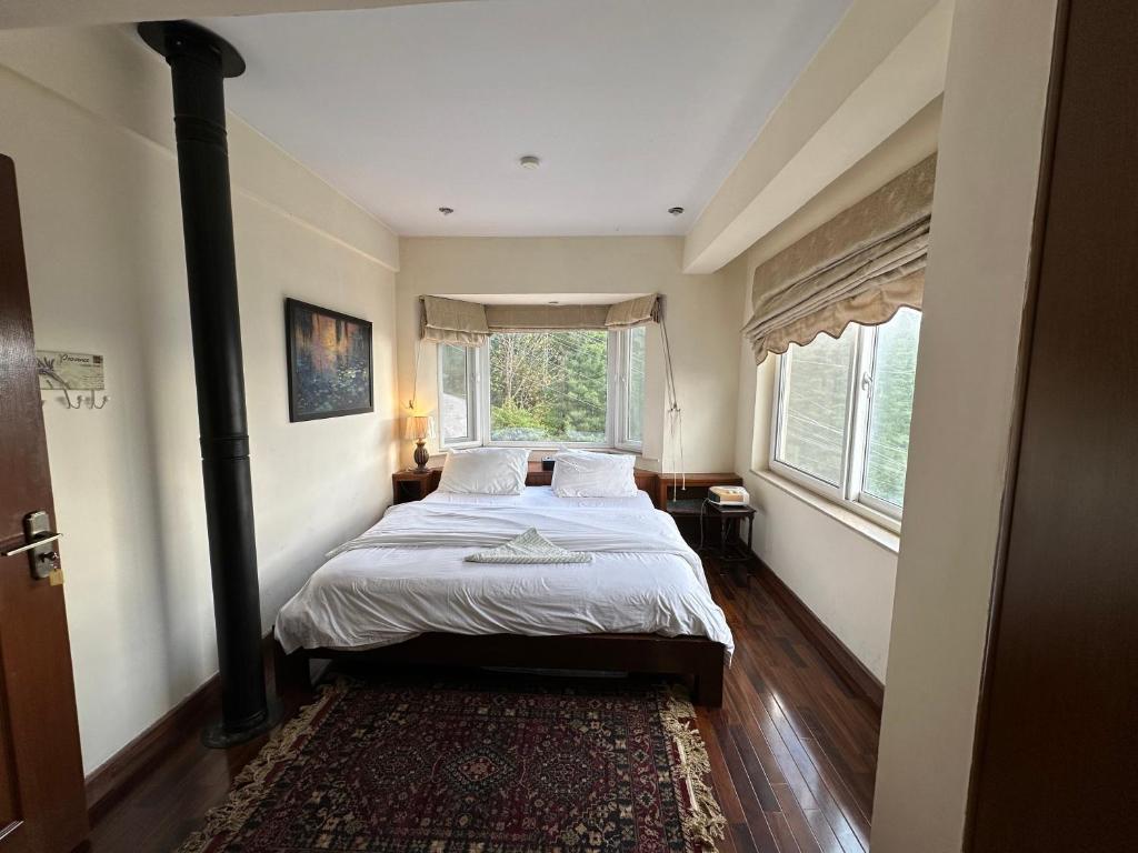 a bedroom with a bed and a large window at Sarah's Lodge in Murree
