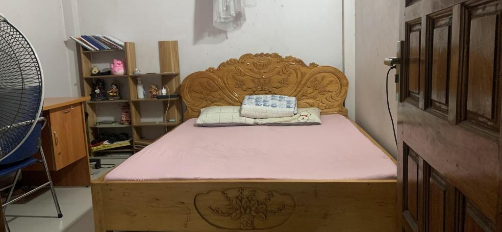 1 cama con cabecero de madera en una habitación en nhà hưng hà, en Dien Bien Phu
