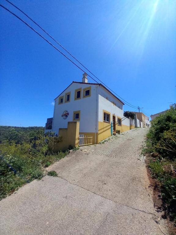 a white and yellow building on a dirt road at Hostel on the Hill in Raposeira