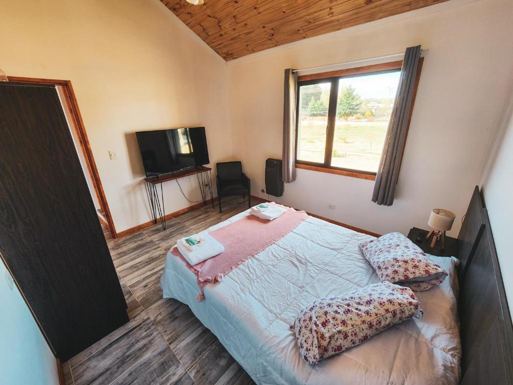 1 dormitorio con cama, ventana y TV en Alquiler Turistico Los Notros en Dina Huapi