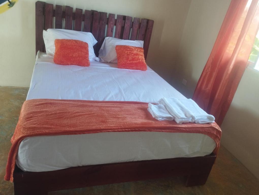 Una cama con dos almohadas rojas encima. en Cabañas Raysa y Alejandro Comprension #4, en Las Galeras
