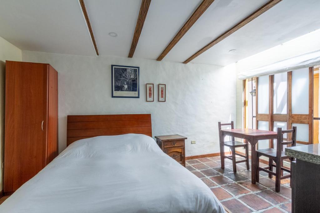 een slaapkamer met een bed en een tafel en stoelen bij Apartaestudios La Candelaria in Bogota