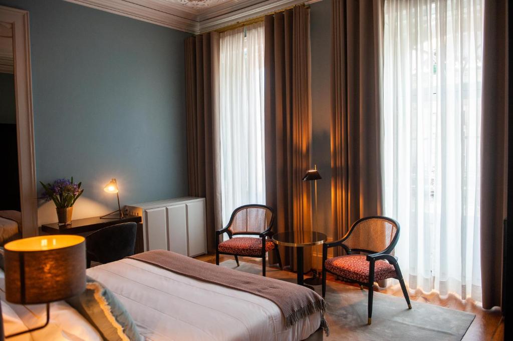 a bedroom with a bed and two chairs and a table at Conquistador Palace in Guimarães