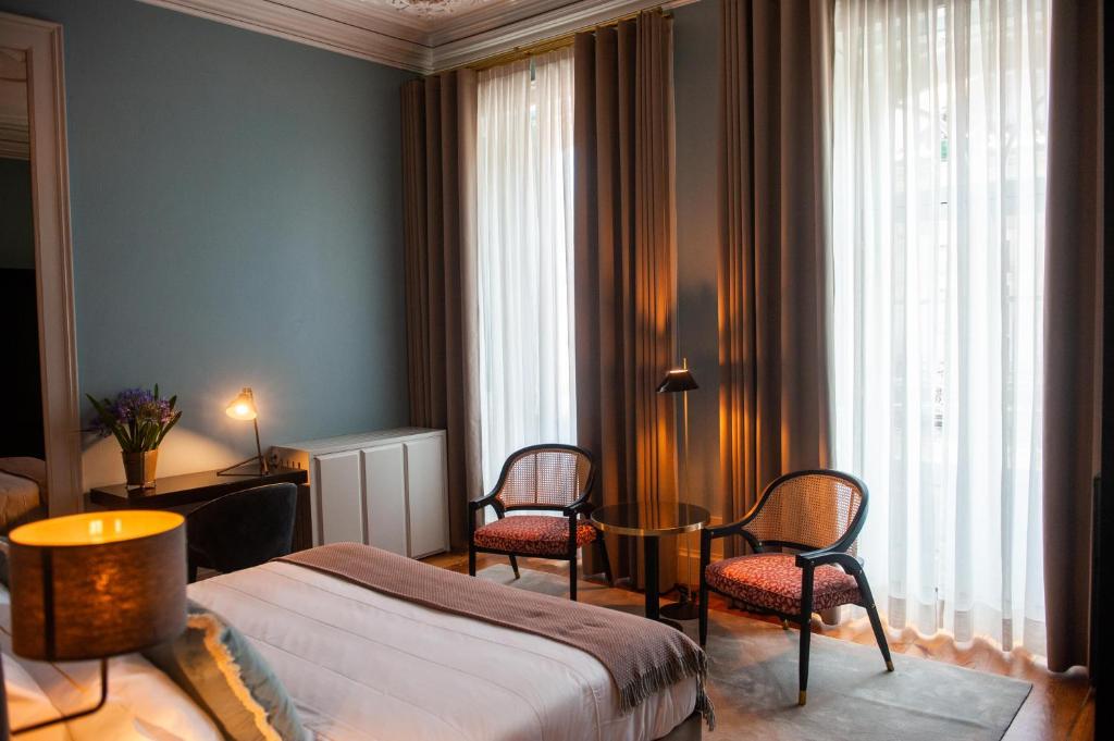 um quarto com uma cama, 2 cadeiras e uma mesa em Conquistador Palace em Guimarães