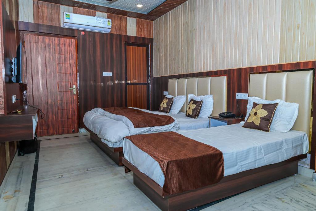 Cette chambre comprend deux lits et une télévision. dans l'établissement Akash Wani Home Stay, à Rishikesh
