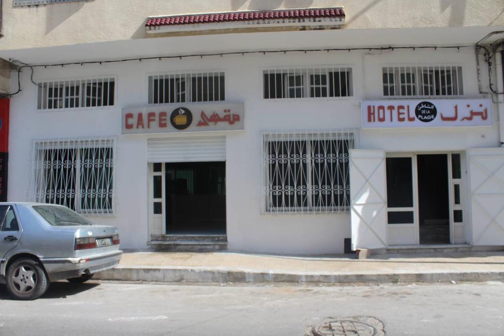 a white building with a car parked in front of it at Hotel de la plage in Bizerte