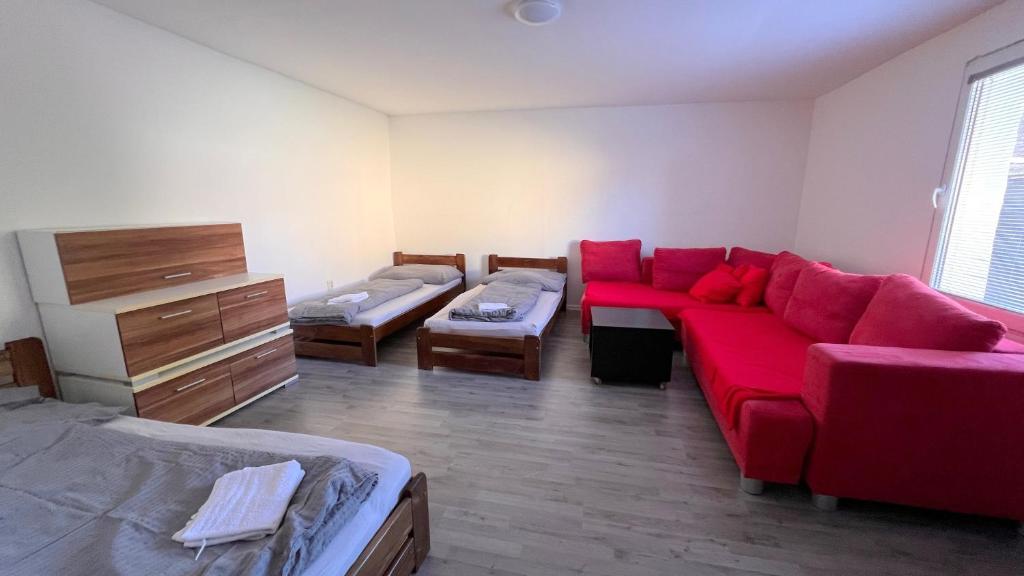 a living room with a red couch and a bed at Apartmánový dom Most pri Bratislave in Senec