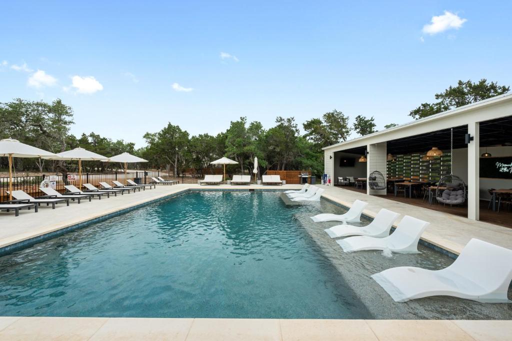 a swimming pool with white lounge chairs and a building at The Cedars Ranch in Wimberley