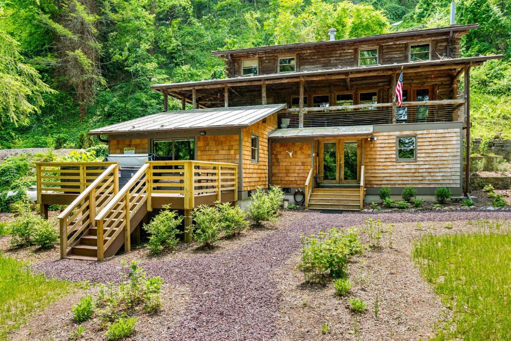 um chalé de madeira com um alpendre e uma bandeira em Riverside Log Cabin w Hot Tub Fire Pit Huge Deck em Rileyville